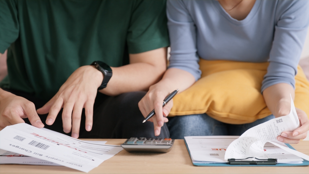 Casal com uma calculadora fazendo contas juntos para entender a composição de renda 